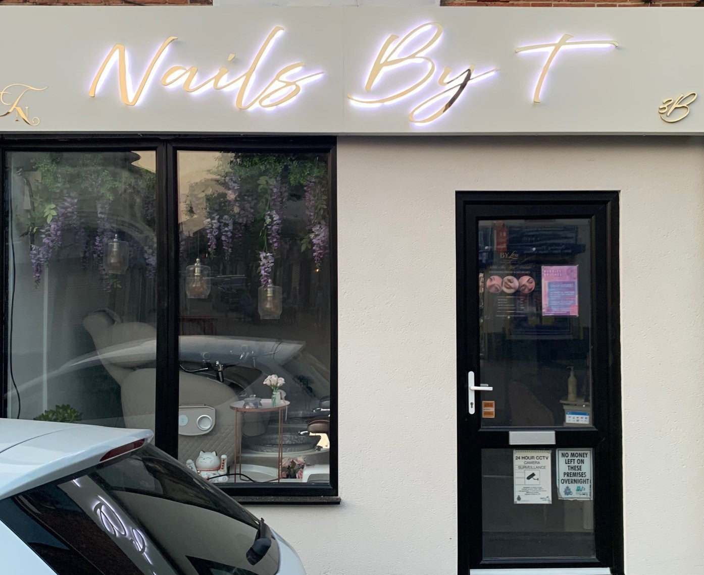 Neon sign 'Nails By T' above a door of a business establishment.